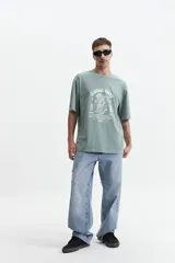 Remera verde con estampado frontal de un tigre y texto en blanco. Corte oversize y mangas cortas.