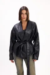 Chaqueta de cuero sintético negro con solapas anchas y cinturón del mismo material para atar en la cintura, de mangas largas y corte holgado.