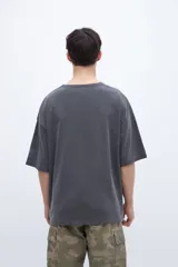 Remera de algodón con calce oversize y textura suave. Presenta un diseño de cuello redondo, mangas cortas con bordado detallado en una de ellas y un acabado de tela lavada.