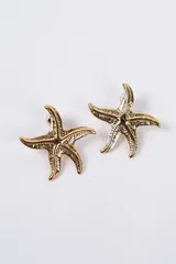 Aros tipo stud con diseño de estrella de mar en acabado plateado con textura rugosa.