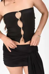 Top strapless negro de tejido acanalado con diseño de aberturas frontales unidas por botones metálicos esféricos.