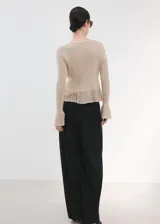 Cardigan de punto fino color beige, entallado, con cuello en V, manga larga acampanada, bajo con volante y cierre frontal con botones.