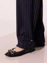 Pantalón de vestir azul marino a rayas verticales blancas, confeccionado en lana sastrera, con cintura sastrera, botas con elástico y tancas para regular.