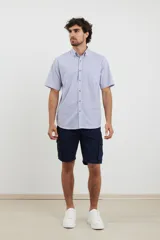 Camisa de manga corta a rayas verticales color celeste y blanco, con cuello abotonado y bolsillo en el pecho.