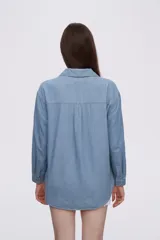 Sobrecamisa celeste de denim con cuello camisero, cierre frontal con botones a presión, dos bolsillos con solapa en el pecho y mangas largas con puños abotonados.