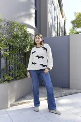 Buzo tejido a mano en lana merino, color crudo con diseño de perro salchicha en negro y detalles de costuras en color naranja en cuello y ruedo.