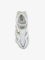 Championes New Balance modelo 9060, con diseño de inspiración Y2K. Presentan una parte superior de malla blanca con superposiciones de gamuza gris y detalles en verde y amarillo. Incluyen el logotipo N característico en los laterales, mediasuela con amortiguación ABZORB y SBS, y dispositivo CR translúcido en el talón.