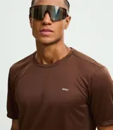 Remera deportiva de manga corta y cuello redondo, confeccionada en tejido de malla de poliéster. Presenta un diseño liso en color marrón con recortes laterales en poliamida.