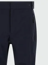 Pantalón técnico de corte recto en color azul marino, con cierre frontal, bolsillos laterales con cremallera y detalle de botón a presión en la cintura.