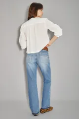 Jean de corte recto y tiro medio, confeccionado en denim de algodón en tono azul lavado. Presenta un diseño clásico con costuras decorativas en los bolsillos traseros y un detalle de bordado sutil en el ruedo.