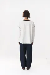 Remera de manga larga con corte oversized, color azul marino con cuello redondo en contraste color marrón. Presenta costuras decorativas a contratono hechas a mano en la zona de los hombros y logo bordado en el centro del pecho.