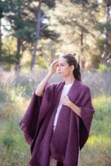 Ruana de lana merino extrafina con tejido texturizado, diseño envolvente y flecos en los extremos. Prenda versátil de corte amplio y sin género.