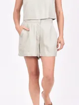 Short color gris claro de tiro alto, con bolsillos laterales y cierre frontal con botón y cremallera.