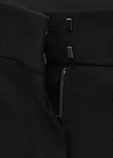 Pantalón flare de talle medio con diseño largo, trabillas en la cintura y cierre frontal de botón, gancho y cremallera.