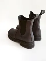 Bota tipo Chelsea de caña media, confeccionada en cuero negro con acabado mate. Presenta paneles elásticos laterales, tiradores traseros y suela track robusta con plataforma dentada.