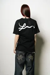 Remera negra de corte regular fit, con un pequeño parche ovalado estampado en el pecho y un gran logo de estilo manuscrito en la espalda.