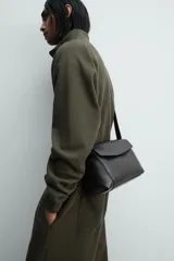 Bolso bandolera negro de piel con textura, cierre de solapa con imán y cremallera. Incluye bolsillo interior con cremallera y bolsillo plano. Asa de hombro ajustable de piel.