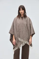 Ruana de lana sin teñir en tonos beige, con textura acanalada y terminaciones con flecos en los bordes.