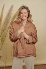 Campera tipo kimono acolchada en color azul petróleo, con diseño de costuras verticales y bolsillos frontales amplios. Presenta mangas largas con puños vueltos y un corte holgado y abierto.