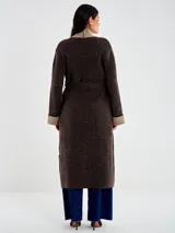 Saco largo de tejido de punto marrón oscuro con micro lentejuelas sutiles. Presenta un cuello chal ancho en color beige/tostado, puños doblados a tono y bolsillos aplicados. Se ajusta con un lazo o faja del mismo tejido principal.