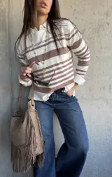 Sweater de punto fluido con diseño de rayas horizontales en color beige y blanco, de manga larga y silueta relajada.