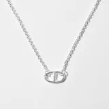 Collar plateado con cadena de eslabones finos y dije con forma de doble letra T entrelazada.