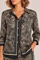 Camisa de satén con estampado animal print tipo cebra en tonos camel y negro, con cuello camisero, botonadura frontal y puños anchos con ribetes.