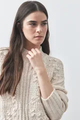 Polera de tejido de punto color marrón, con cuello alto y diseño de textura con relieves y trenzas. Posee mangas largas con puños acanalados.