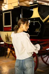 Blusa de algodón con estampado a cuadros vichy en tonos beige y blanco. Presenta un diseño con volados en el escote, mangas largas amplias y puños con volados.