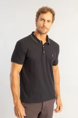Camisa polo de manga corta en color negro, confeccionada en tejido piquet. Presenta cuello y bordes de mangas con detalles de frisos tricolor, cierre frontal de tres botones y logo bordado en el pecho.