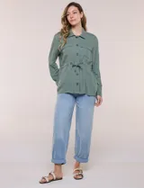 Sobrecamisa beige de lino liviano, con cuello camisero, cierre frontal de botones carey y bolsillos en el pecho. Cuenta con cordón ajustable en la cintura y mangas largas.