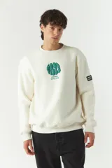 Buzo de felpa color crudo con cuello redondo y estampado frontal con el texto 'Good Vibes' y el logo de la marca Mistral. Tiene un parche con el logo de la marca en la manga izquierda.