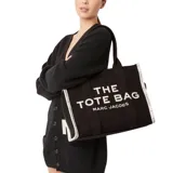 Bolso tote de gran tamaño confeccionado en tejido jacquard, color negro con letras en contraste. Presenta cierre superior con cremallera, doble asa superior y diseño espacioso con múltiples bolsillos interiores.