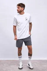 Remera blanca de manga corta con cuello redondo y estampado frontal de un teléfono antiguo con el texto "Early Check Out".