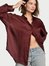 Camisa de satén semitransparente color bordó, de corte ligeramente holgado y diseño abotonado al frente con mangas largas y cuello.