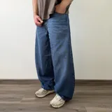 Pantalón jean de corte barrel, color azul clásico con efecto desgastado y diseño amplio y curvado en las piernas.