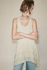 Vestido corto de viscosa color crudo, con escote redondo, manga sisa y diseño en jacquard con aplicaciones de abalorios. Presenta múltiples paneles superpuestos y bajo asimétrico.