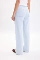 Pantalón jean de corte ancho y tiro alto, con estampa de rayas finas celestes y blancas, bolsillos laterales y cierre frontal con botón metálico.