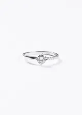 Anillo de plata 925 con una piedra central redonda engarzada en cuatro puntas y una mitad del cuerpo del anillo pavimentada con zirconias pequeñas.