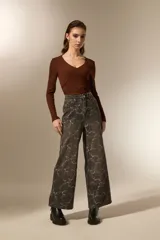 Pantalon de jean estilo baggy con estampado floral en tonos gris oscuro y blanco. Presenta un corte de pierna ancha, tiro medio y cierre frontal con botón y cremallera.