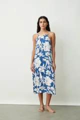 Vestido midi de corte holgado con estampado floral en tonos azul y blanco, presenta escote halter con breteles finos y diseño sin mangas.
