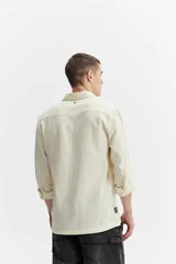 Camisa rústica de manga larga color gris oscuro, con cuello clásico, cierre frontal con botones y un bolsillo aplicado en el pecho.