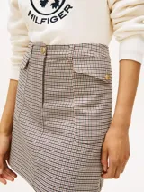 Mini falda de corte recto con estampado de cuadros en tonos beige y marrón. Presenta un diseño clásico con cierre frontal y estructura definida.