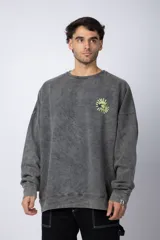 Buzo de cuello redondo y corte oversize, confeccionado en tela friza con efecto de teñido artesanal desgastado. Presenta un estampado pequeño en color verde lima en el pecho y una etiqueta pequeña en el puño.