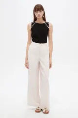 Pantalon sastrero ancho de tiro alto, color beige, con bolsillos y cierre frontal con botón.