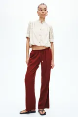 Pantalón de pierna recta en tejido liviano mezcla de lino y viscosa, color rojo. Cuenta con cintura elástica de tiro bajo, cordón de ajuste con cuentas decorativas en los extremos y bolsillos laterales al bies.