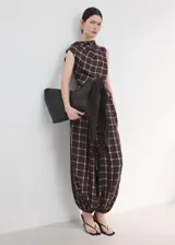 Pantalón balloon de tiro medio en color marrón oscuro con estampa de cuadros. Cuenta con cintura ajustable con goma y cierre de lazo, además de dos bolsillos laterales y diseño abuchonado en los tobillos.