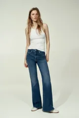 Jean de tiro alto y cinco bolsillos confeccionado en denim azul con leve elasticidad. Presenta un corte ajustado desde la cintura hasta las caderas y diseño acampanado desde la rodilla hacia el bajo.