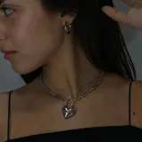 Gargantilla plateada de eslabones gruesos con dije de corazón inflado.