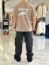 Remera oversize de efecto lavado color marrón, con diseño gráfico estampado en la espalda que incluye texto y una estrella estilizada.